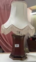 A wood effect lamp base with fringed shade