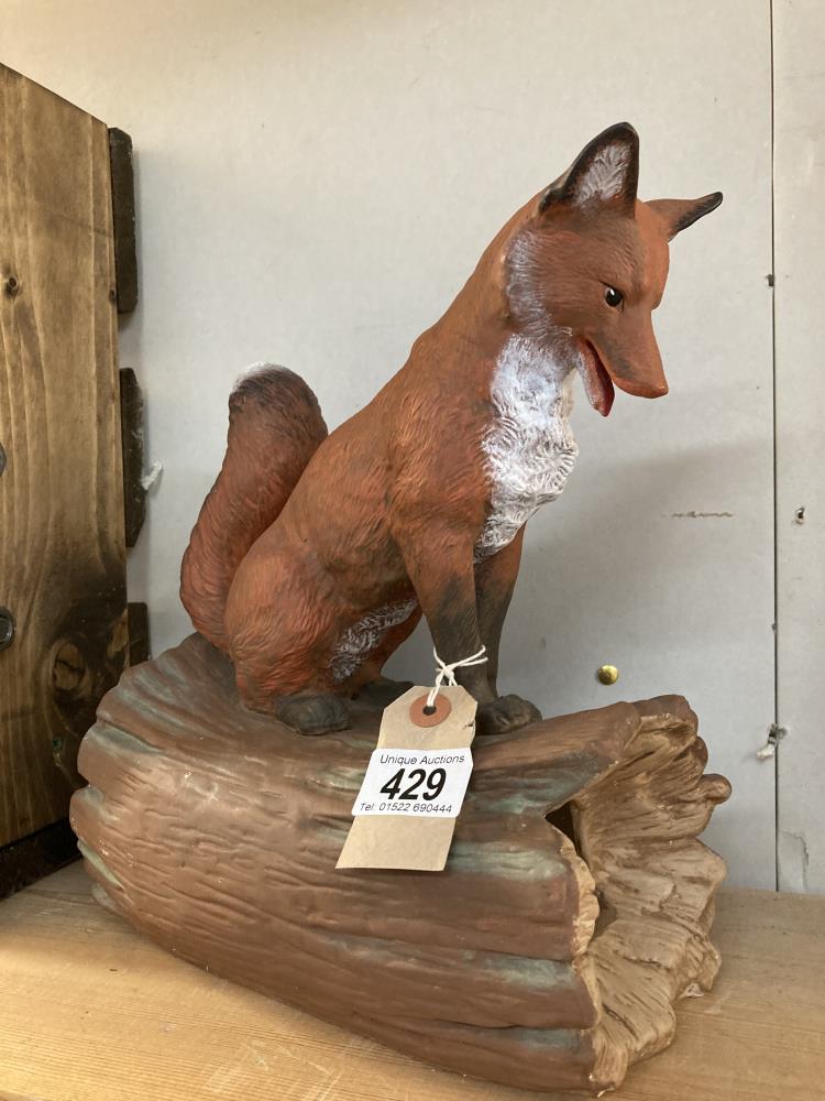 A ceramic fox sitting on log signed Yozie Height 28cm, Width 20cm, Depth 14cm