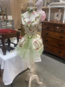 A Mannequin with green netting and a satin style flower bodice and embellishments