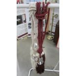 A pair of red wine curtain tie backs with ribbon and gem effect embellishment and tassels and a pair