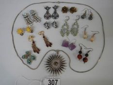 A sunburst pendant and twelve pairs of assorted earrings.