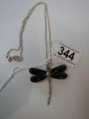 A silver dragonfly pendant with black onyx wings on a silver chain.