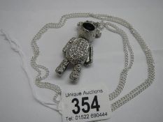A white metal articulated teddy bear on a long chain.