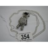 A white metal articulated teddy bear on a long chain.