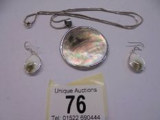A silver shell pendant and earrings.