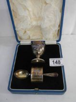 A boxed silver egg cup, spoon and napkin ring set.