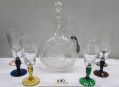 A glass claret jug engraved with birds and 6 engraved glasses with coloured stems.