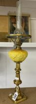 A 19th century brass drop in font candlestick oil lamp with yellow glass font and chimney.