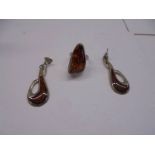 A silver and amber ring, size N and a pair of white metal and amber earrings.