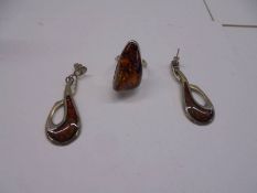 A silver and amber ring, size N and a pair of white metal and amber earrings.