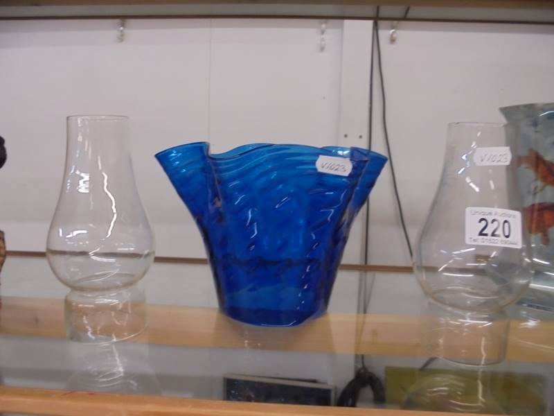 A blue glass oil lamp shade and two oil lamp chimneys.