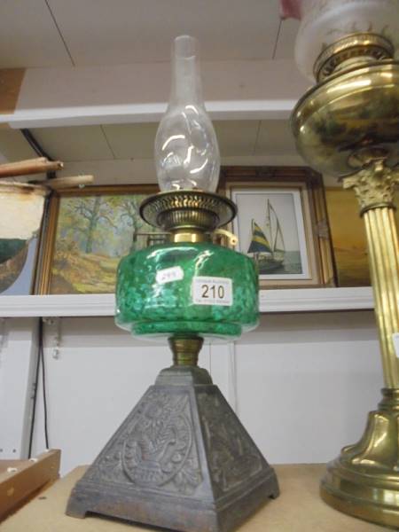 An early 20th century oil lamp on cast iron base with green glass font and chimney. COLLECT ONLY.