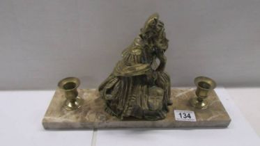 A bronzed figure of and old lady on an marble base and with candleholders.