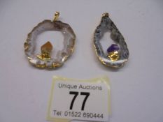 Two crystal and yellow metal pendants.
