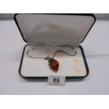A silver and amber pendant on a 41 cm chain in original box.