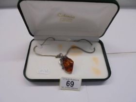 A silver and amber pendant on a 41 cm chain in original box.