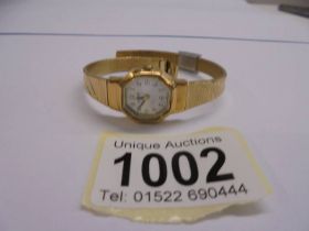 A Lorus ladies wrist watch on a yellow metal bracelet.