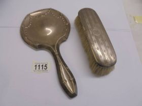 A silver hand mirror and a silver hair brush.