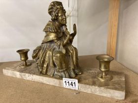 A brass figured candle stand on polished stone base
