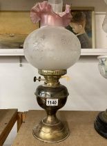 A brass oil lamp with frosted shade