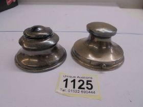 Two silver inkwells.