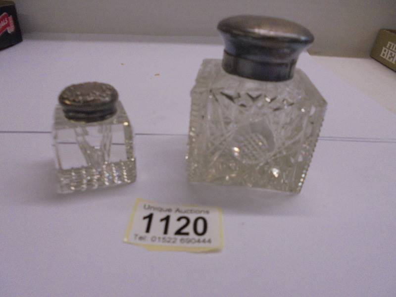 Two glass inkwells with silver tops.
