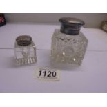 Two glass inkwells with silver tops.