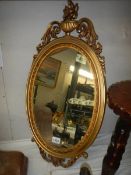 A gilt framed oval mirror. COLLECT ONLY.