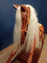 Wooden rocking horse with leather saddle and harness. { 114cm H X 190cm L X 46cm D }.