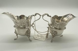 Pair of Irish silver milk jugs with hand chased florals to the top rim with an open monogram
