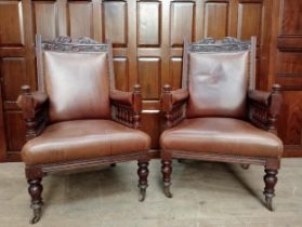 Pair of oak and leather arm chairs raised on turned legs and castors {H 105cm x W 66cm x D 70cm }.
