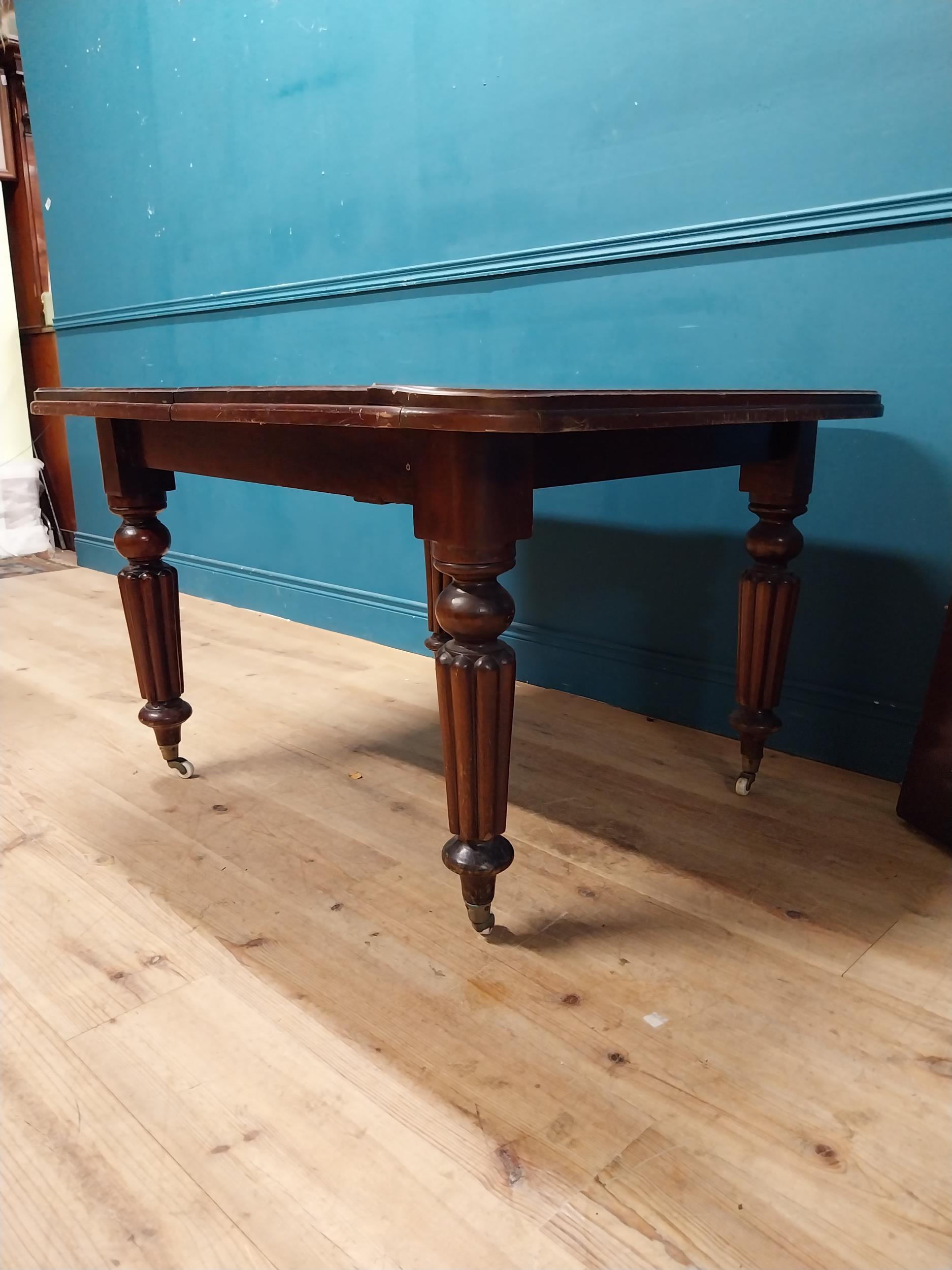 Victorian mahogany dining room table with one extra leaf raised on turned legs and brass and castors - Image 4 of 5