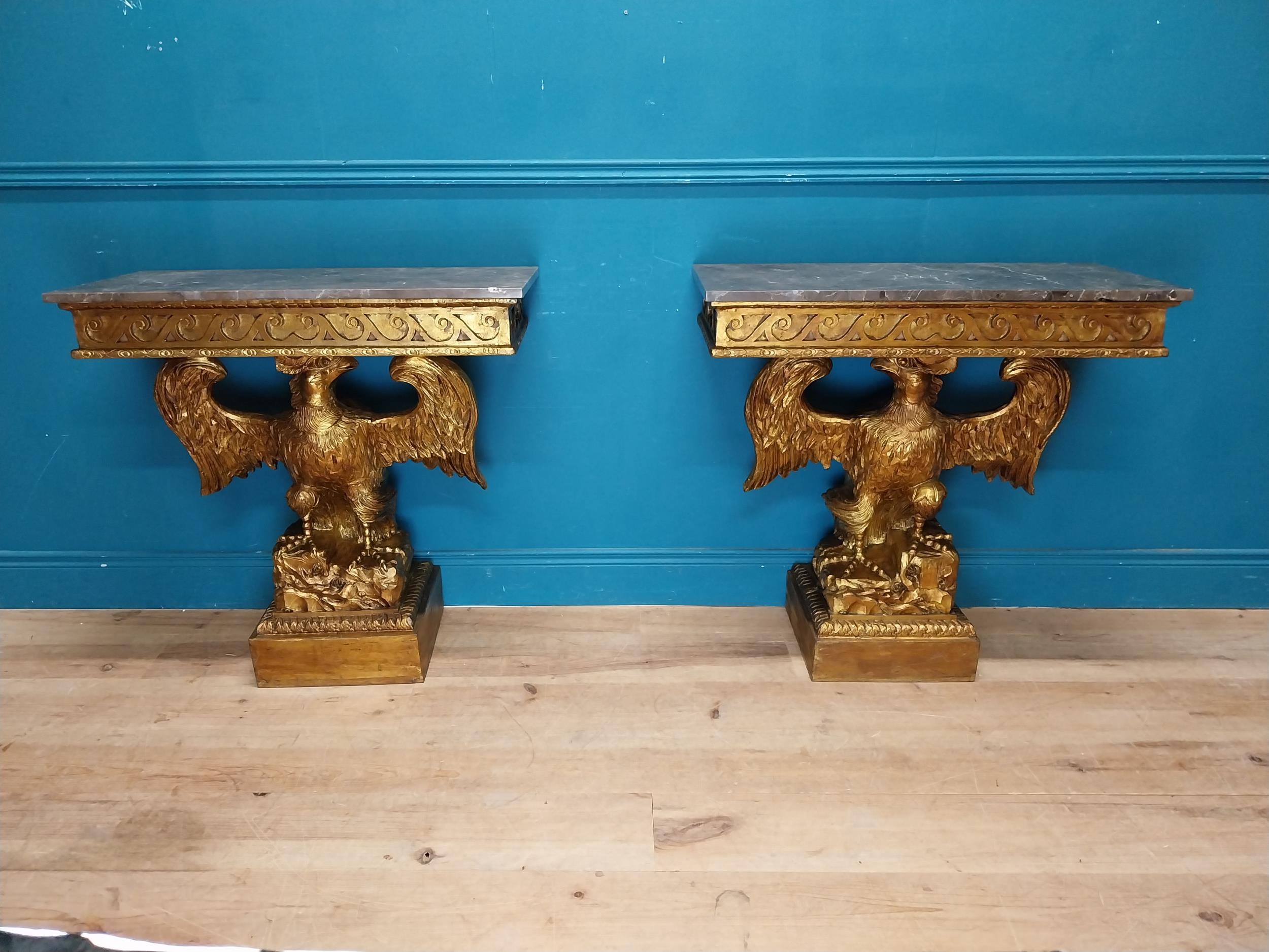 Pair of gilt cast metal marble topped console tables with outspread eagles on base in the William