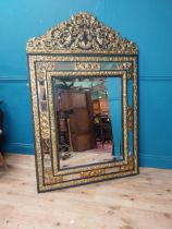 19th C. French brass and ebonised cushion mirror surmounted with cherub and flora and foliage
