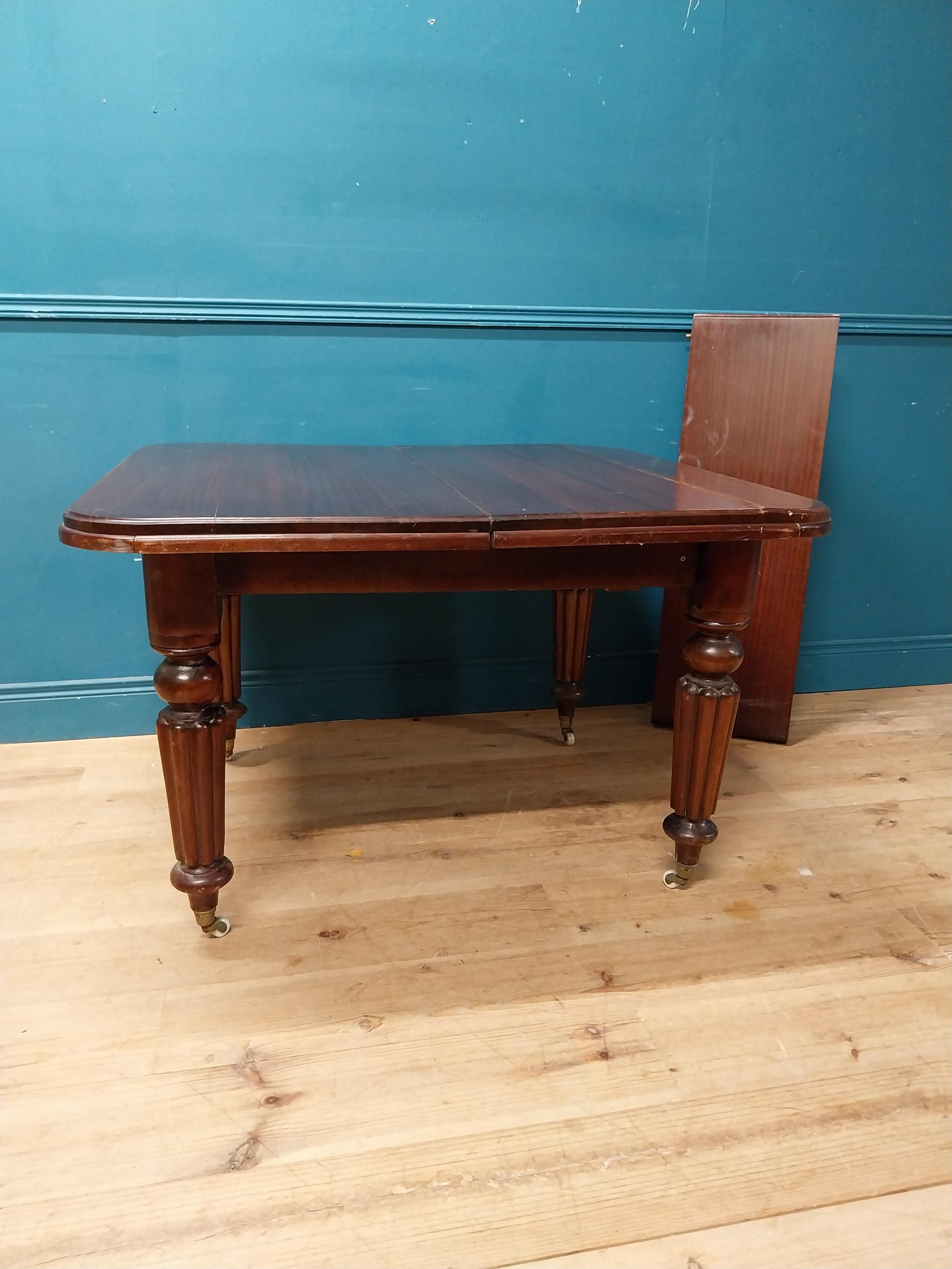 Victorian mahogany dining room table with one extra leaf raised on turned legs and brass and castors