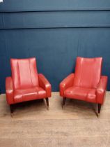 Pair of retro red leather armchairs raised on brass legs{}.