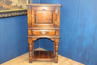 18th C. side cabinet with single blind door above single drawer raised on turned legs and platform