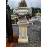 Pair of good quality moulded sandstone urns decorated with rams heads and raised on pedestals { }