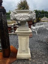 Pair of good quality moulded sandstone urns decorated with rams heads and raised on pedestals { }