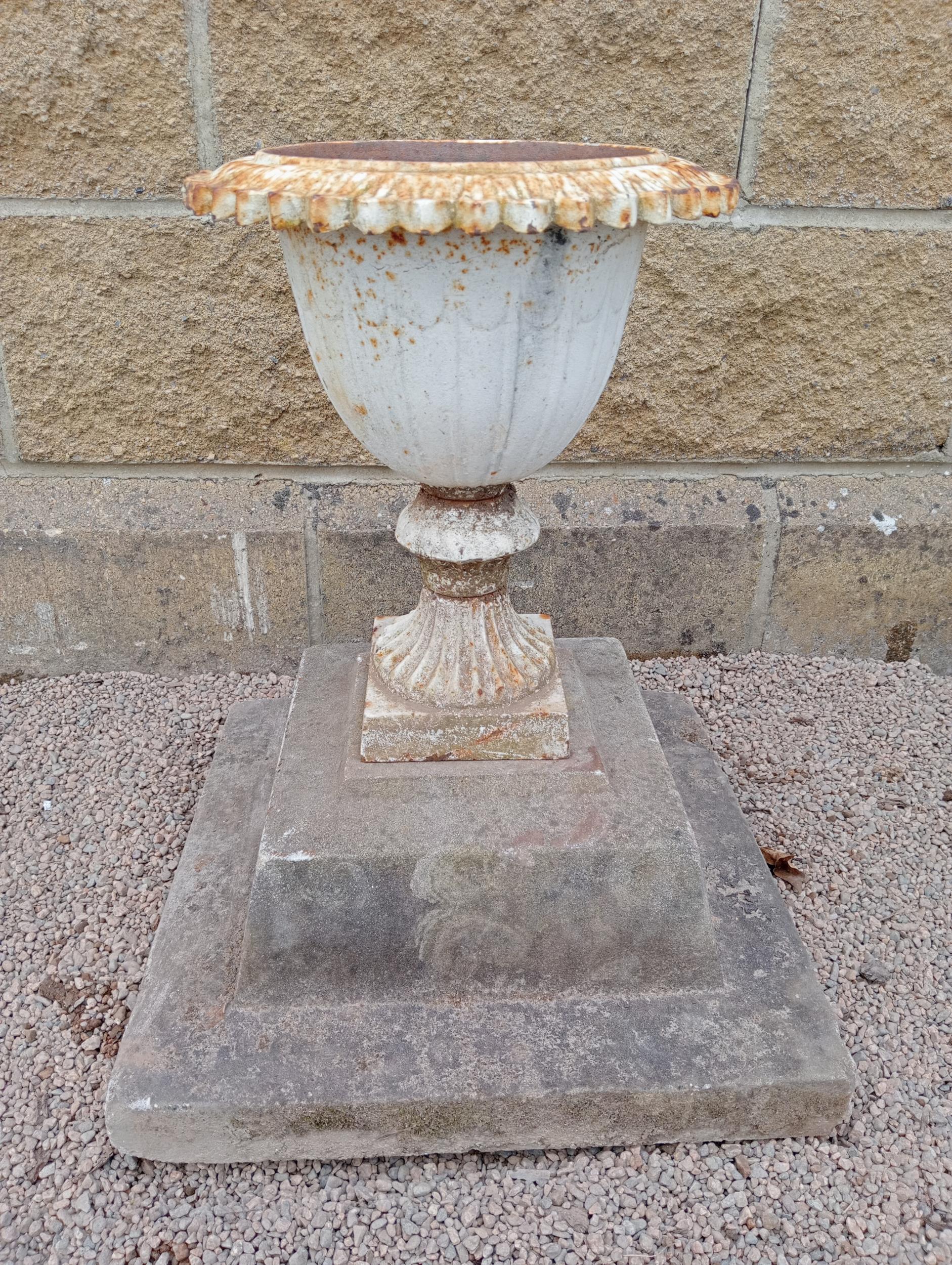 Cast iron urn on stone base {H 50cm x W 43cm x D 43cm }. (NOT AVAILABLE TO VIEW IN PERSON)