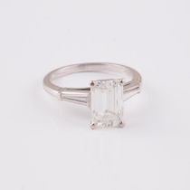 Platinum Solitaire Ring, set with an emerald cut diamond (3.05ct.; SI1; G) flanked by 2 tapered bagu