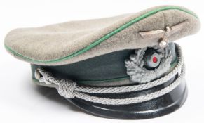 A Third Reich Infantry officer's peaked cap, with metal insignia, silver bullion cords, and green