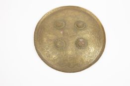 An Indian decorative brass shield "Dhal", 13½" in diameter, chased, punched and engraved overall