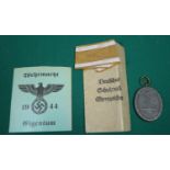 A Third Reich "West Wall" medal, in its printed paper packet with a length of ribbon; an