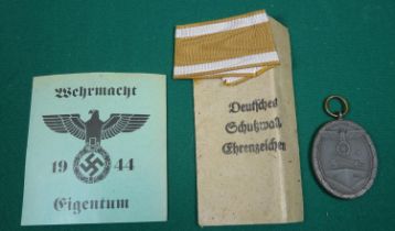 A Third Reich "West Wall" medal, in its printed paper packet with a length of ribbon; an
