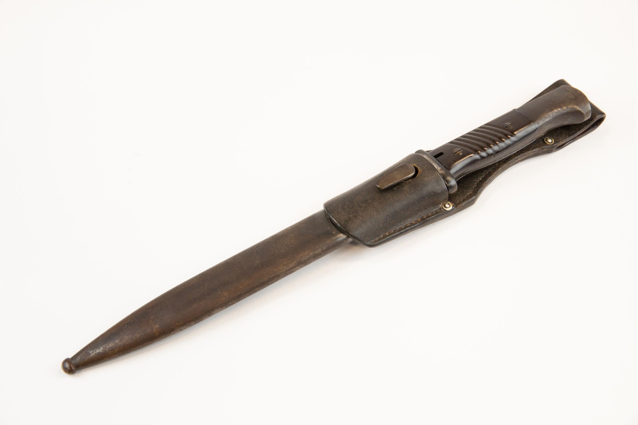 A WWII German K98 bayonet, with brown bakelite grips, in its scabbard with leather frog, the bayonet