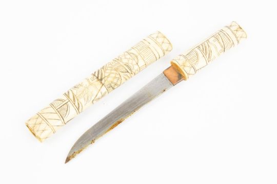 A simple Japanese bone dagger, blade 6½", the hilt and sheath carved with scenes of figures and