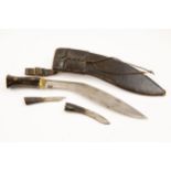 A kukri, blade 12", the hilt having horn grips and brass mounts, in its leather covered sheath