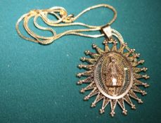 An 18K gold hallmarked chain with a large filigree sunburst style pendant with a small building to
