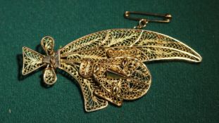 A possibly 18K gold unmarked yellow metal filigree brooch, depicting what looks like leaves tied
